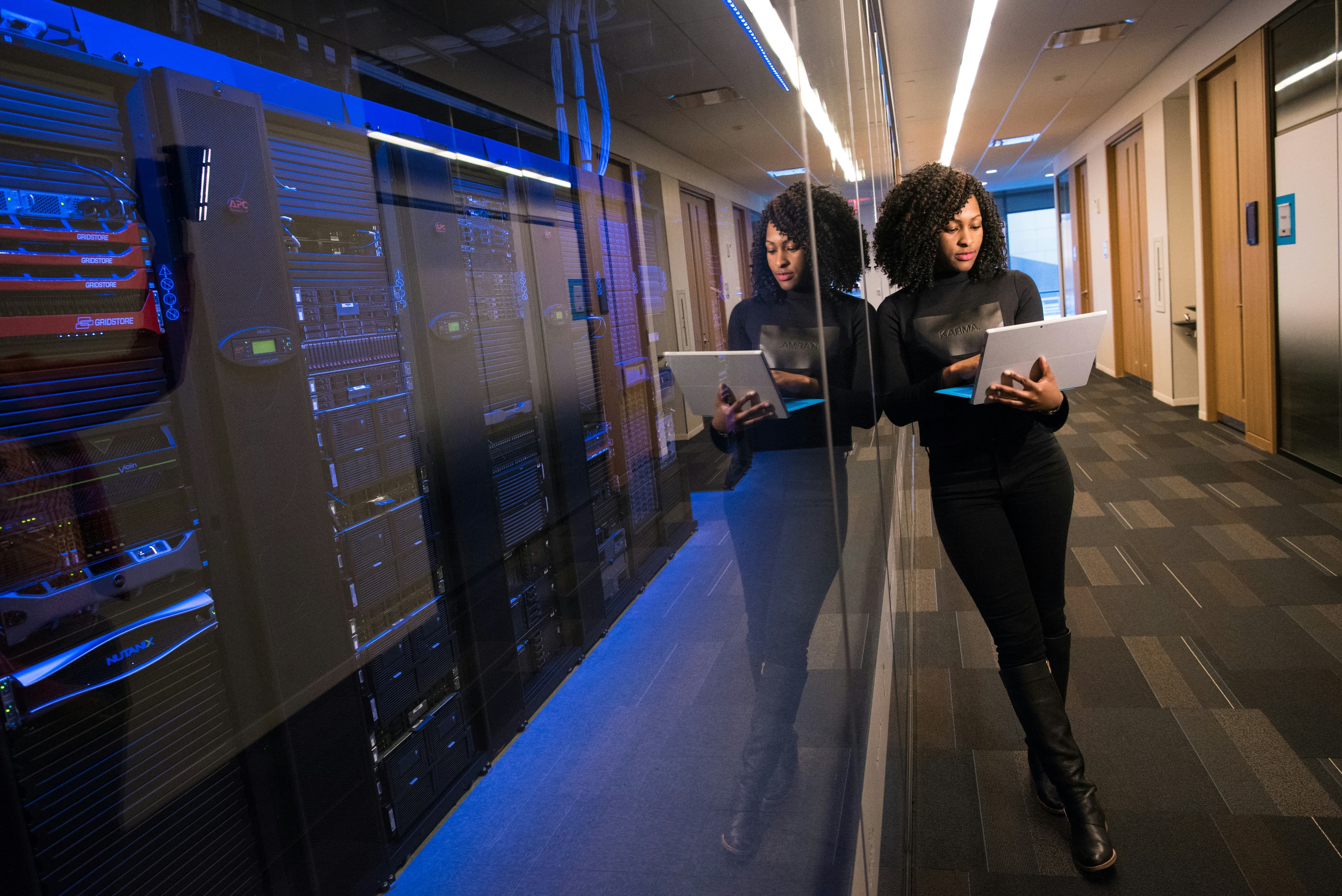 Image of person standing next to a server using a computer.